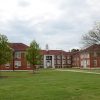 Multistory brick building with cupola and two wings on college campus