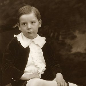 White boy sitting in collared shirt and shorts with legs crossed