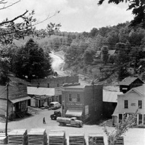 Town buildings with trucks and wood piles on dirt roads