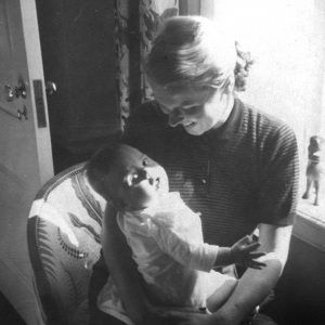 white woman smiling in chair with baby boy in her arms