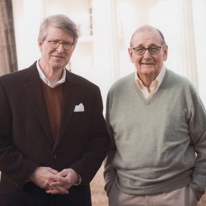 Two older white men with glasses smiling