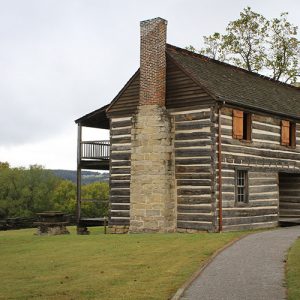 Two-story log cabin with brick chimney and balcony on backside