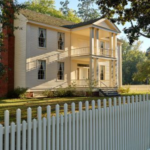 Multistory house with covered porch and balcony inside wooden fence