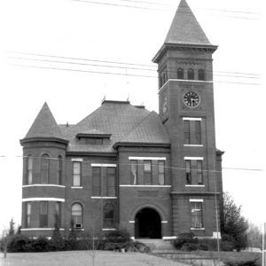 Multistory brick courthouse with clock tower and arched entrance on a hill