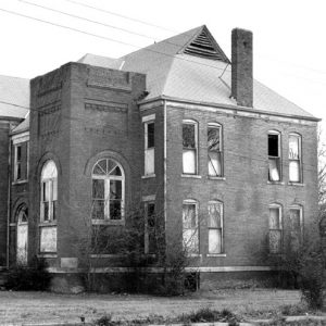 Two-story brick building with arched windows and arched doorway