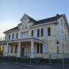 Abandoned multistory house with yellow paint behind a fence