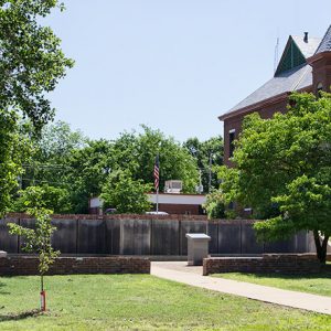 Memorial wall and plaque on pedestal and brick wall next to brick courthouse