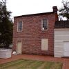 Rear view of two-story brick building adjoining single-story structure with wood siding on museum grounds