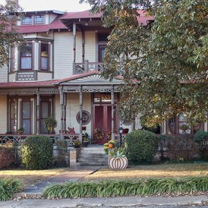 ornate two-story house with covered porch and balcony on street