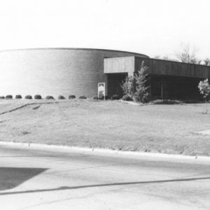 Round brick building on a hill with parking lot