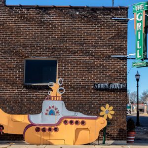 Cartoonish yellow submarine sculpture and Abbey Road sign on side of "The Grill" restaurant building