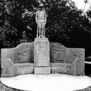 Statue of soldier on top of engraved memorial wall