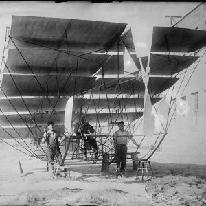 Multi-wing aircraft with on in cockpit and two other people standing beside it