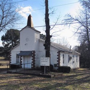 Single-story white church building with steeple