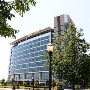 Multistory building with windowed front side tower landscaping driveway and pedestrians