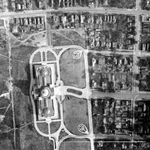 view from above of Two-winged building with three domes surrounding symmetrical sidewalks city grid and field behind