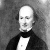 Balding white man in suit with black collar