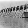 Concrete dam with water rushing over it and lake