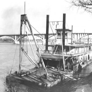 Boat on the Arkansas River with concrete bridge in the background