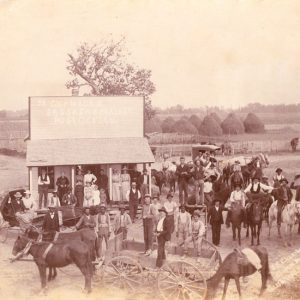 Crowd of people in hats and some in horse drawn carriages at "J.R. Chambers's" store