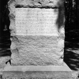 Stone marker with square base and trees in the background