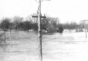 Flooded street with small house and telephone poles