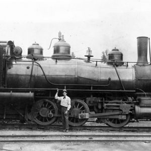 White engineer posing, standing with hand on locomotive