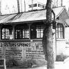 Forest shed with pitched roof wrap around windows wall text "McFadden 3 Sisters Springs"