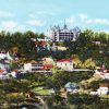 Hand tinted photograph hillside town with large hotel on peak