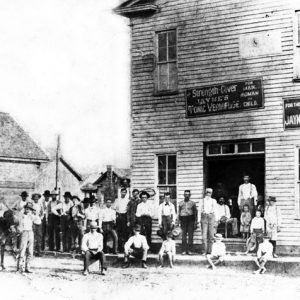 Group photo men children mule outside two-story wooden building with signs "Jayne's tonic vermifuge"