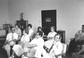 Group of white men and women sitting in chairs indoors