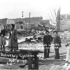 White women and men with damaged buildings behind them, photograph labeled "Brinkley Cyclone"