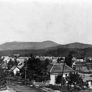 Town view from elevated forest road with mountains in background