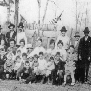 Group of white men women and children gathered around "Alta Villa" sign