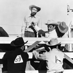 Six white cowboys in rodeo chute preparing for event