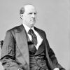 Portrait white man balding stern expression three piece suit tie seated on carved wooden chair