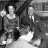 White man and woman formal dress laughing at party with two white people foreground