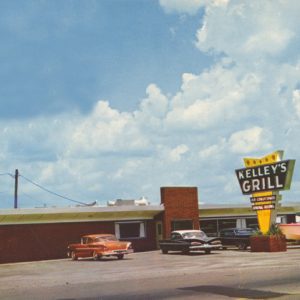 Modern restaurant and sign "Kelley's Grill," parking lot, cars, boat and trailer