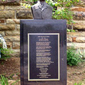 Black stone monument with bust on top and plaque on its front