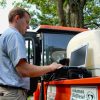 white man using laptop stands at back of utility truck labeled "Arkansas Biodiesel Project"