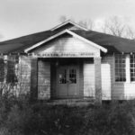 Clapboard school house with double doors and chimney