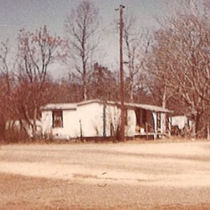 Rural gas station with two pumps and houses across the street