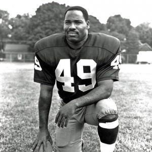 African-American man in number 49 uniform with kneeling with football