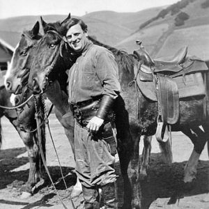 White man in cowboy outfit posing with horses