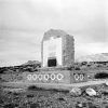 Stone marker with bird icon engraved text plaque patterned base in desert with mountain background