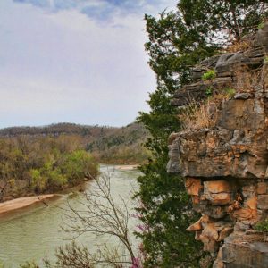 elevated view past a rocky bluff overlooking a river that curves off and disappears into some hills