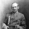 white man in military regalia posing with saber