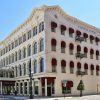 four-story white stone building with red awnings over each side window and words "Capital Hotel" at top