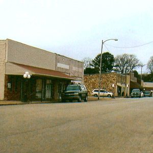 Single-story store front buildings on street with parked cars