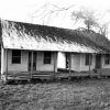 Clapboard dogtrot-style house with brick chimney and trees